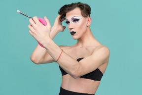 Drag queen, die haare fixiert, während sie in den spiegel schaut