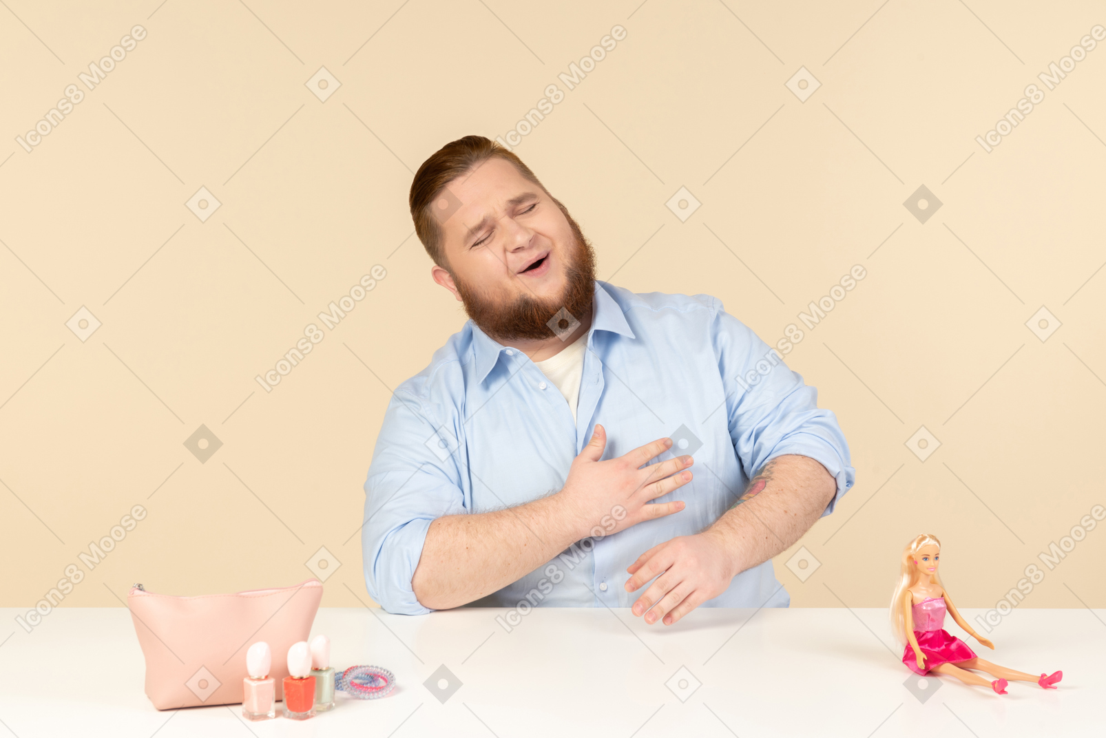 Rire grand homme assis à la table avec des produits cosmétiques et poupée barbie sur elle