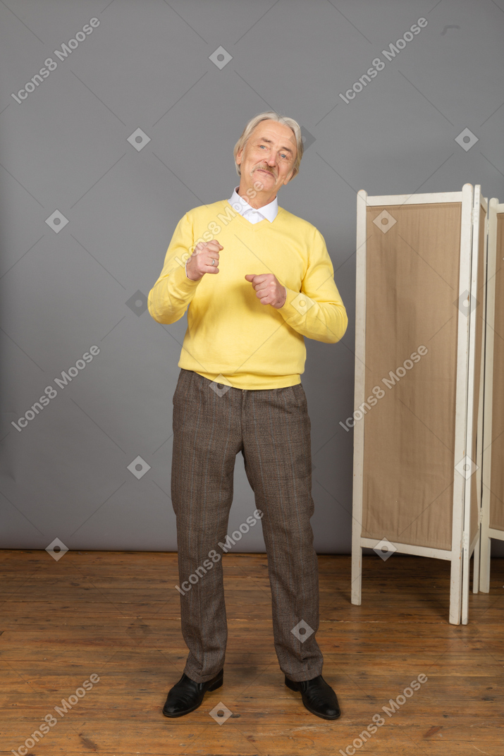 Vista frontale di un uomo anziano sorridente soddisfatto che stringe i pugni
