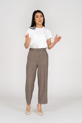 Vista frontal de una mujer joven en pantalones y camiseta blanca que muestra el tamaño de algo