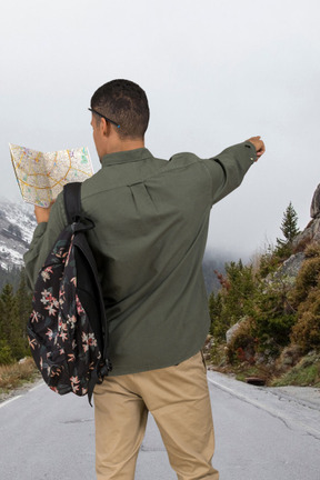 A man with a backpack looking at a map