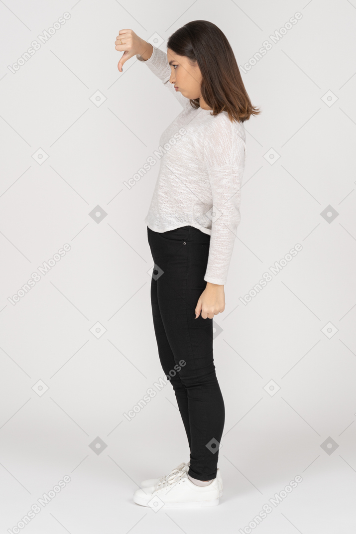 Side view of a young indian female in casual clothing showing thumb down