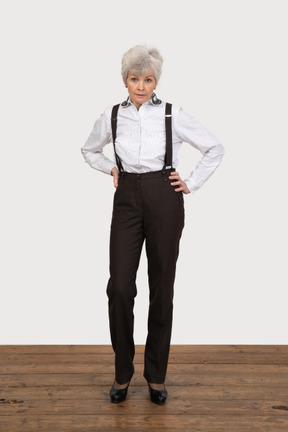 Vista frontal de una anciana disgustada en ropa de oficina poniendo las manos en las caderas
