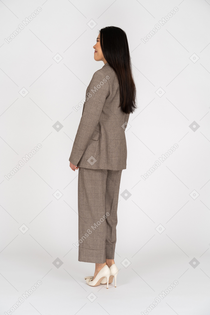 Three-quarter back view of a grimacing young lady in brown business suit