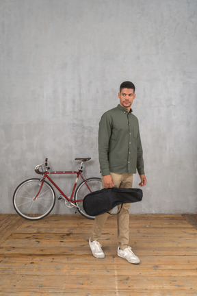 Front view of a man carrying a ukulele case