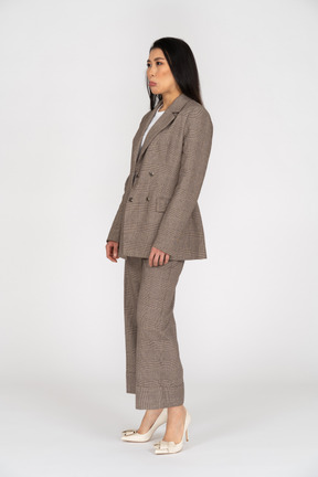 Three-quarter view of a displeased pouting young lady in brown business suit