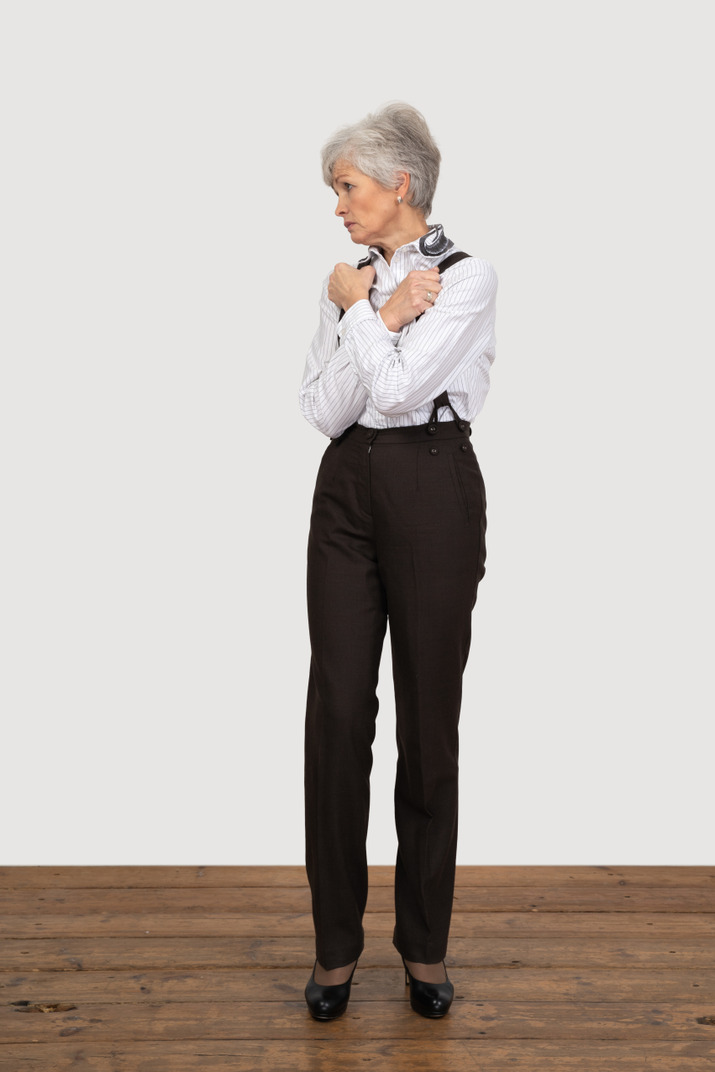 Front view of an old lady in office clothing crossing hands and clenching fists