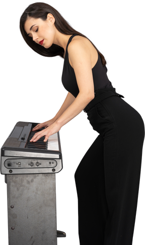 Vista laterale di una giovane donna in abito nero a suonare il pianoforte