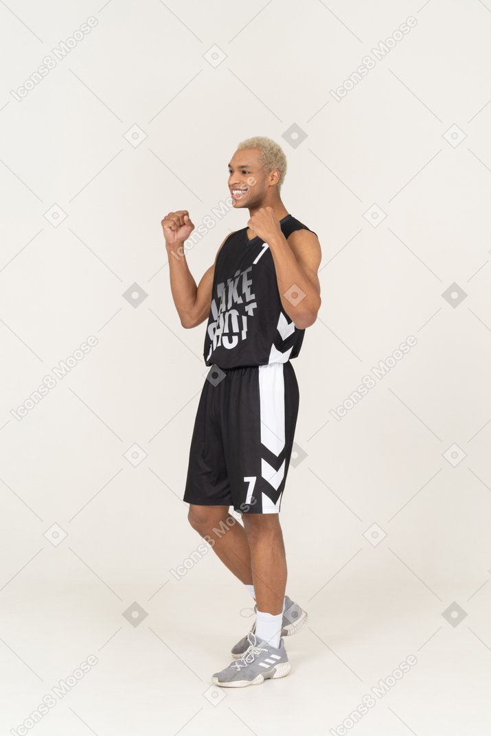 Three-quarter view of a happy young male basketball player raising hands