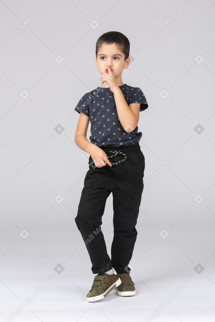 Vista frontal de um menino fofo fazendo um gesto de shh