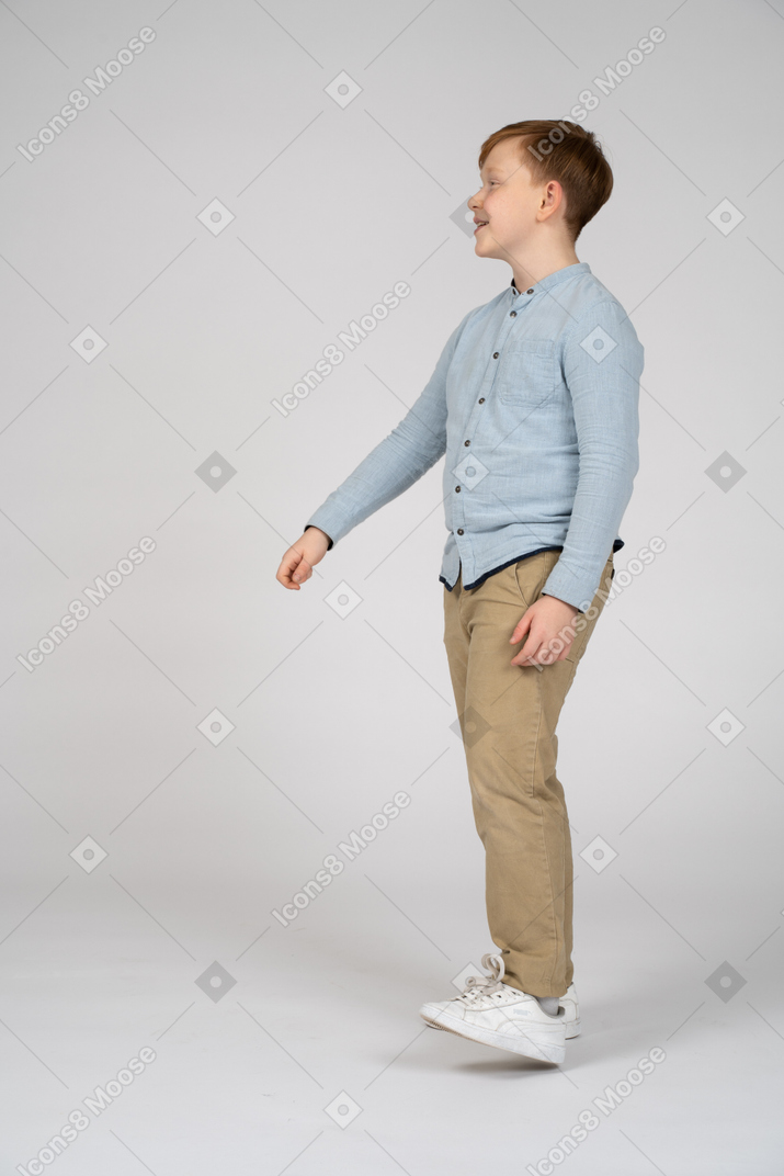Side view of a happy boy with standing with extended arm