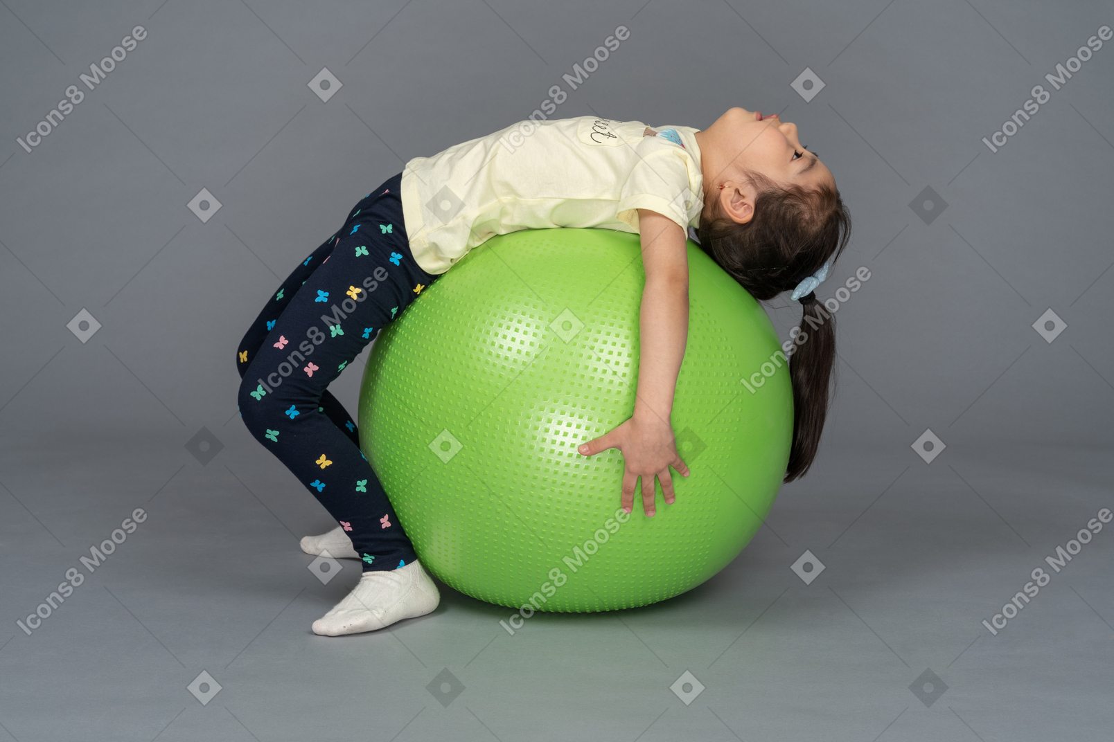 Little girl lying on a green fitball on her back