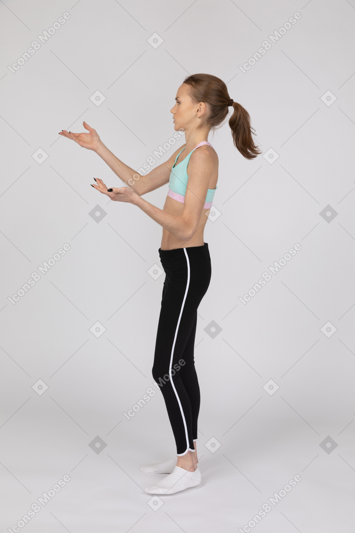 一个十几岁的女孩在运动服举手和争论的侧视图