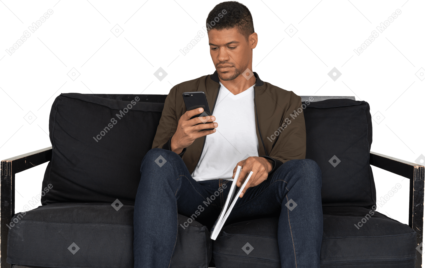 電話を使用しながら雑誌を保持しているソファに座っている若い男の正面図