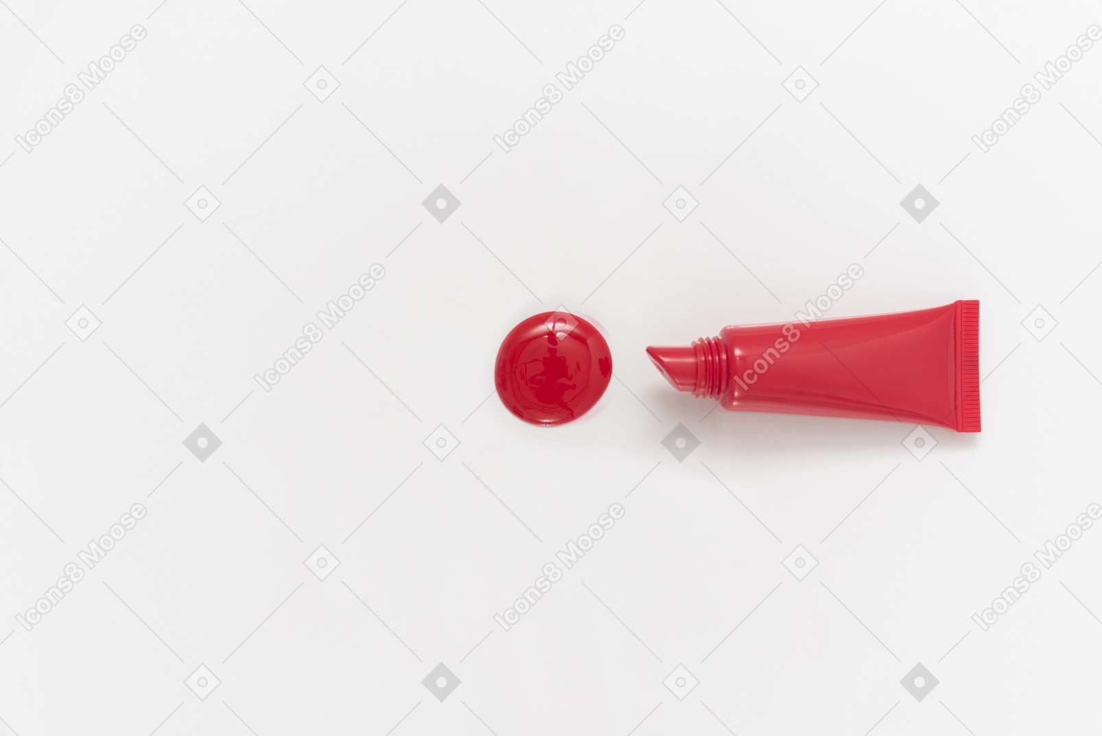 Gota de lápiz labial rojo y botella de lápiz labial sobre fondo blanco.
