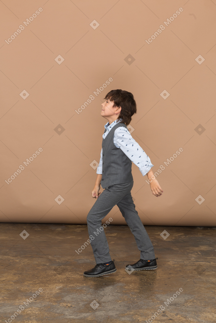 Side view of a boy in grey suit walking