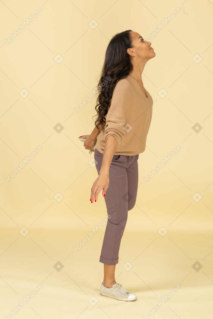 一个深色皮肤的年轻女性，抚摸她的脚踝的侧视图