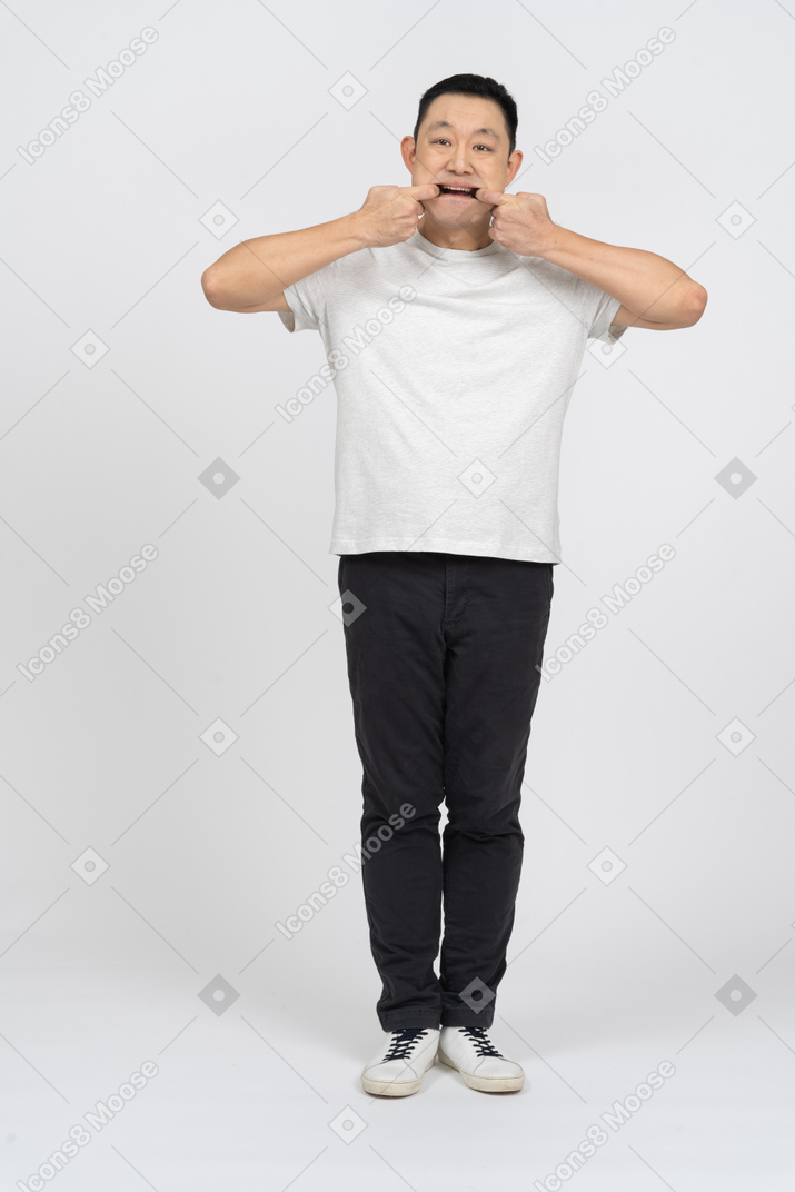 Vue de face d'un homme en vêtements décontractés mettant les doigts dans la bouche et regardant la caméra
