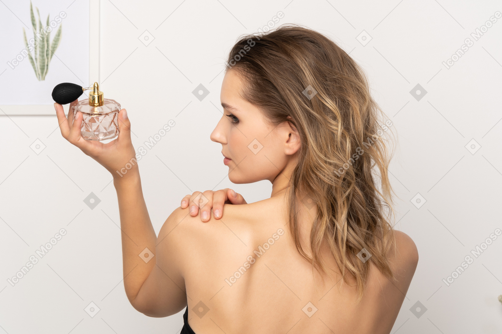 Back view of a sensual young woman holding a bottle of perfume