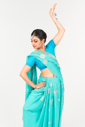 Joven mujer india en sari azul de pie en posición de baile