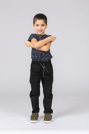 Vista frontal de um menino fofo posando com os braços cruzados