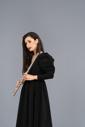 Front view of a young lady in black dress holding flute