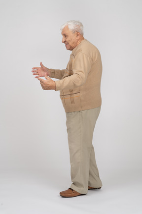 Side view of an old man in casual clothes showing the size of something