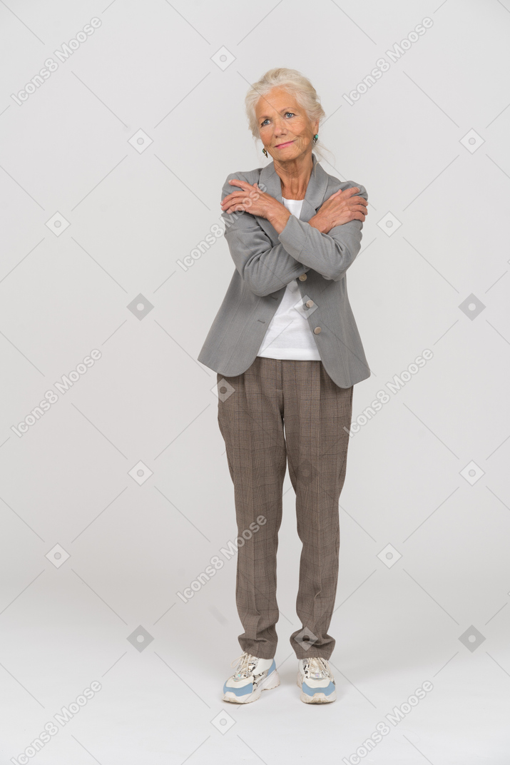 Front view of an old lady in suit hugging herself