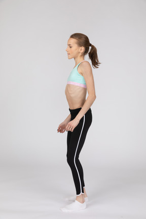 Side view of a teen girl in sportswear tilting shoulders
