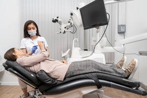 Toute la longueur d'une femme dentiste consultant sa patiente dans une armoire d'hôpital