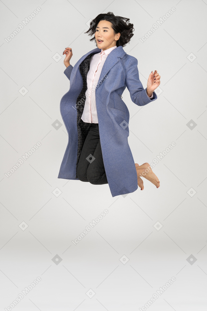 Young woman in coat mid-air