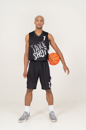 Vista frontal de um jovem jogador de basquete segurando uma bola