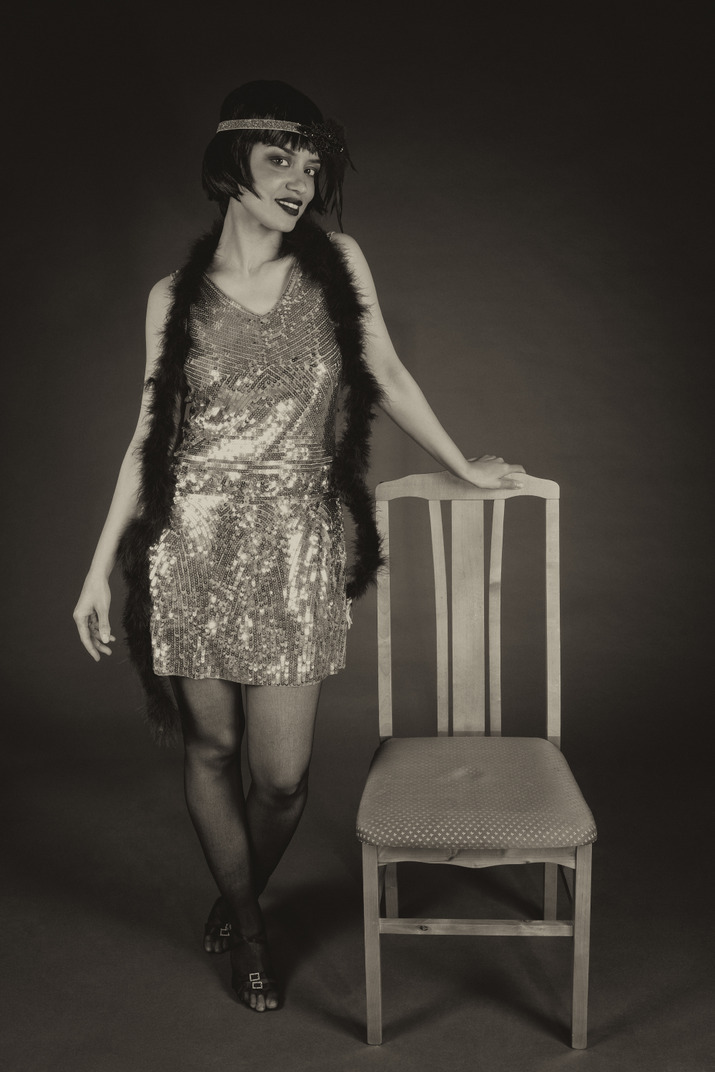 Smiling flapper posing next to a chair