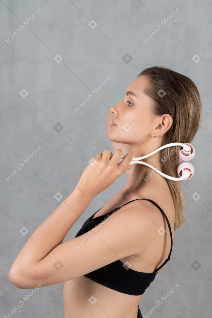 Side view of a young woman holding a face roller