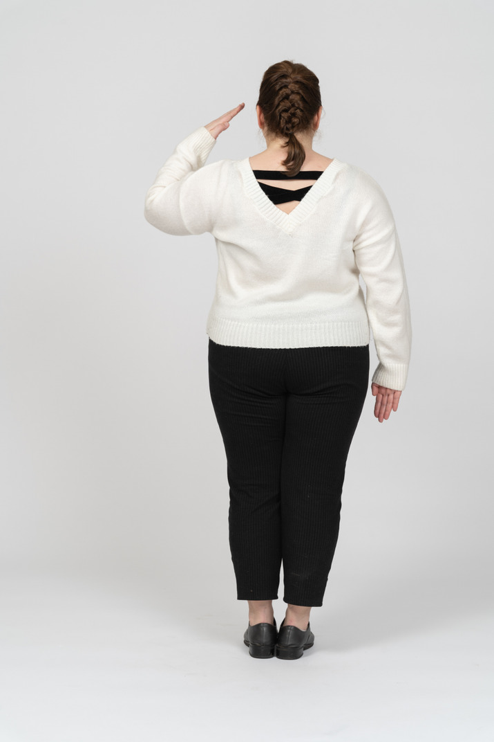 Rear view of a plus size woman in casual clothes saluting with hand