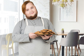 A man with a beard holding a plate of cookies