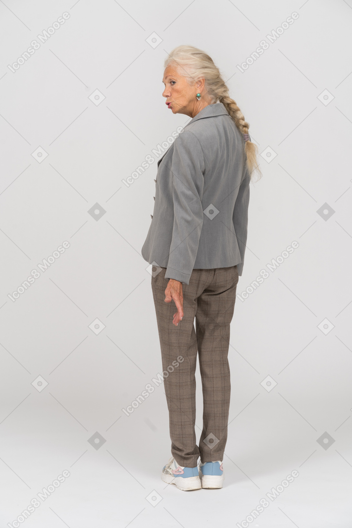 Vista posteriore di una vecchia signora in abito che fa smorfie