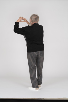 Back view of old man showing heart sign with hands