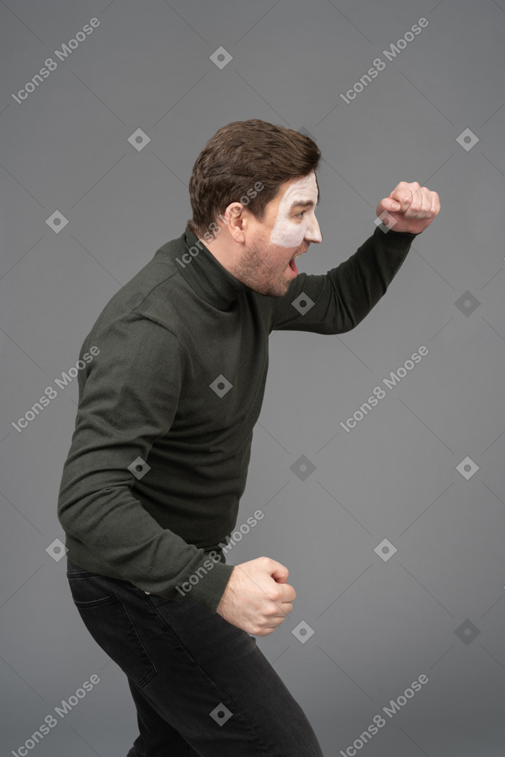 Side view of a cheerful male football fan raising hand & clenching fists