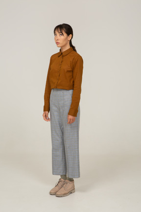 Three-quarter view of a young asian female in breeches and blouse standing still