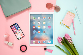 Desk of a modern woman: trendy devices, cosmetics, flowers