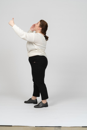 Vista laterale di una donna grassoccia in abiti casual con il braccio alzato