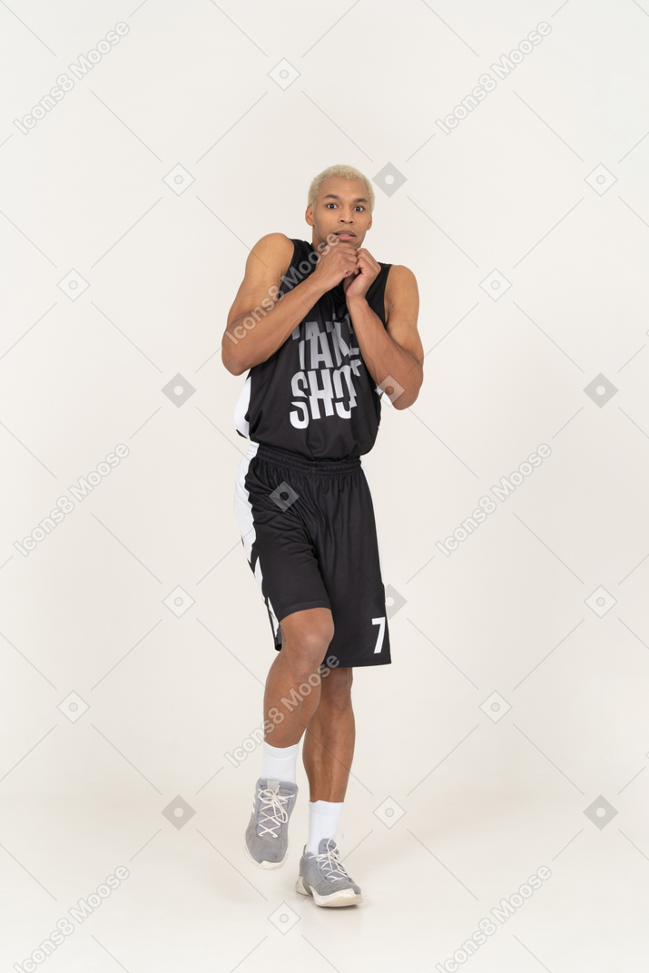 Vista frontal de um jovem jogador de basquete com medo, recostado