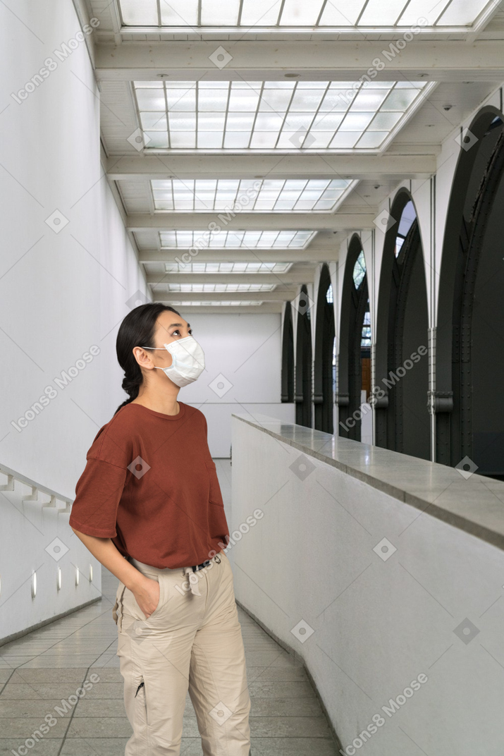 Uma jovem em uma máscara médica, olhando para cima