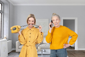 Young woman biting telephone cord while senior woman talking on the phone