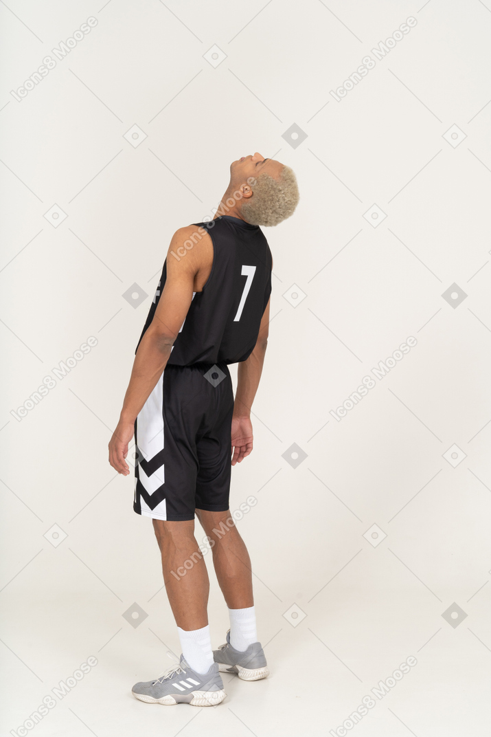 一个疲惫的年轻男篮球运动员向后倾斜的四分之三后视图