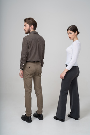 Vista posterior de tres cuartos de una joven pareja cuestionando en ropa de oficina