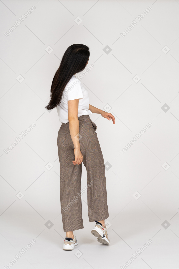 Three-quarter back view of a young lady in breeches and t-shirt turning away
