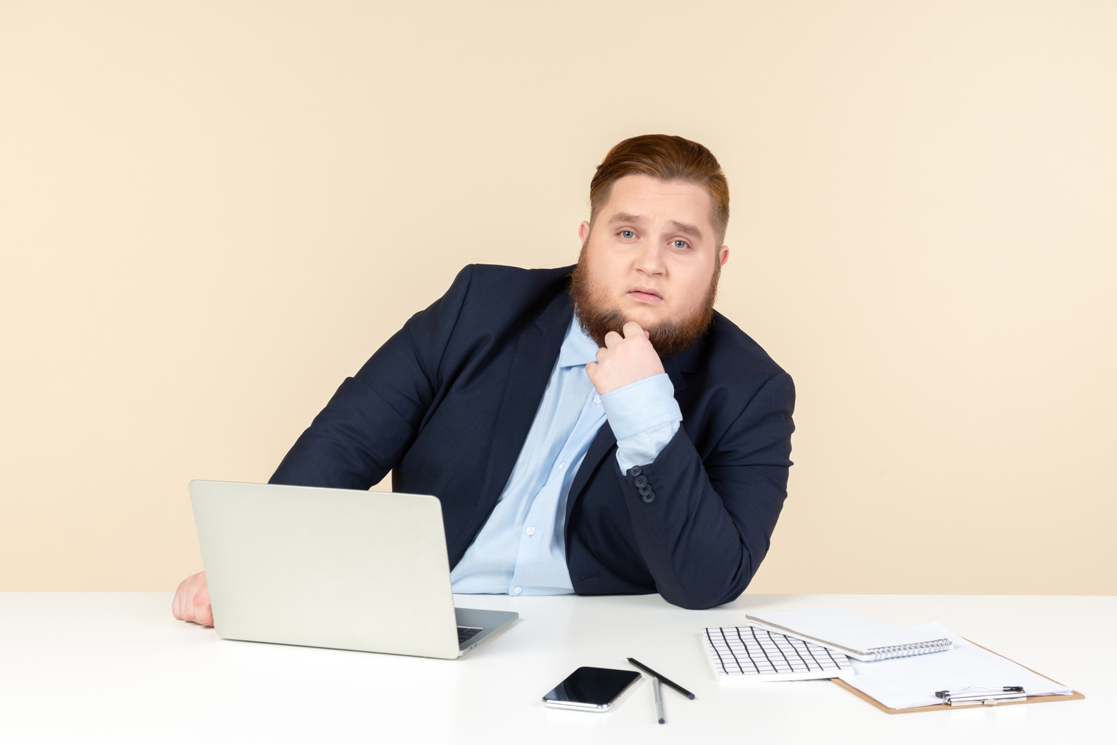 Pensive young overweight office worker sitting at office desk