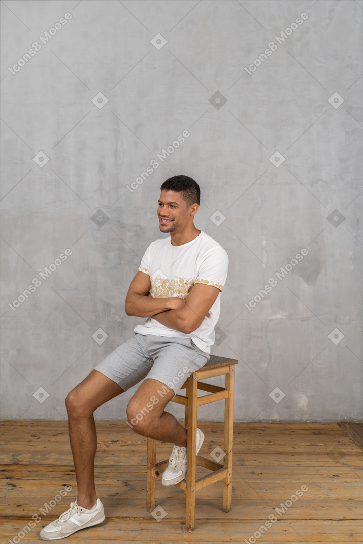 Smiling man sitting on chair with his arms crossed